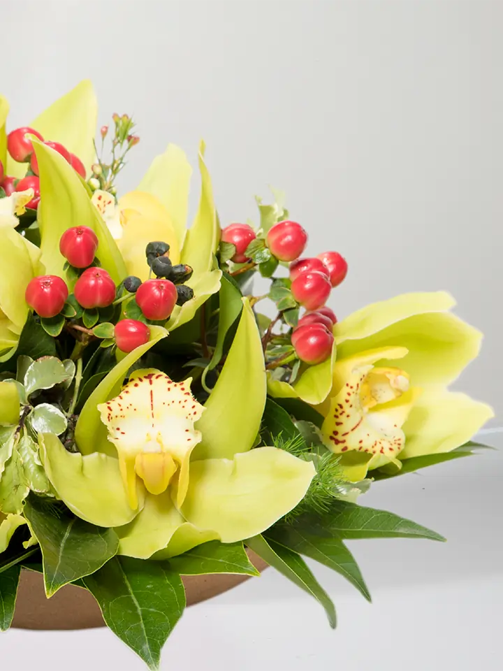 Centrotavola di fiori di cymbidium gialli e bacche rosse macro